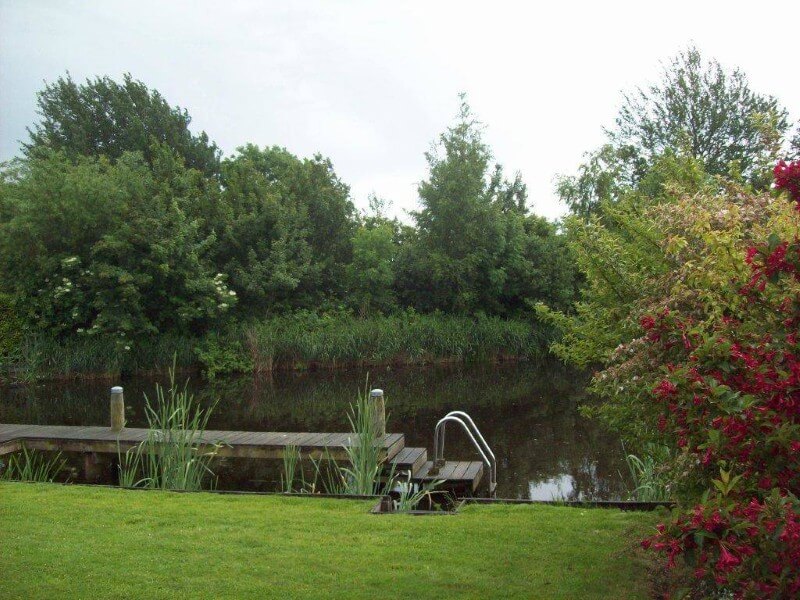 Spelen met je honden in deze ruime tuin aan het water.